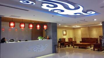 A reception area with a counter, red lanterns, and a seating area with wooden furniture.