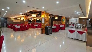 Un amplio salón con filas de mesas y sillas, un escenario y una zona de bufé.