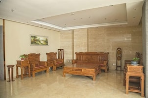 Una habitación amplia con un gran sofá de madera, una mesa de centro y una mesita auxiliar con una planta.
