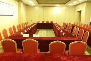 Una sala de conferencias con una larga mesa, sillas rojas y tarjetas de identificación.