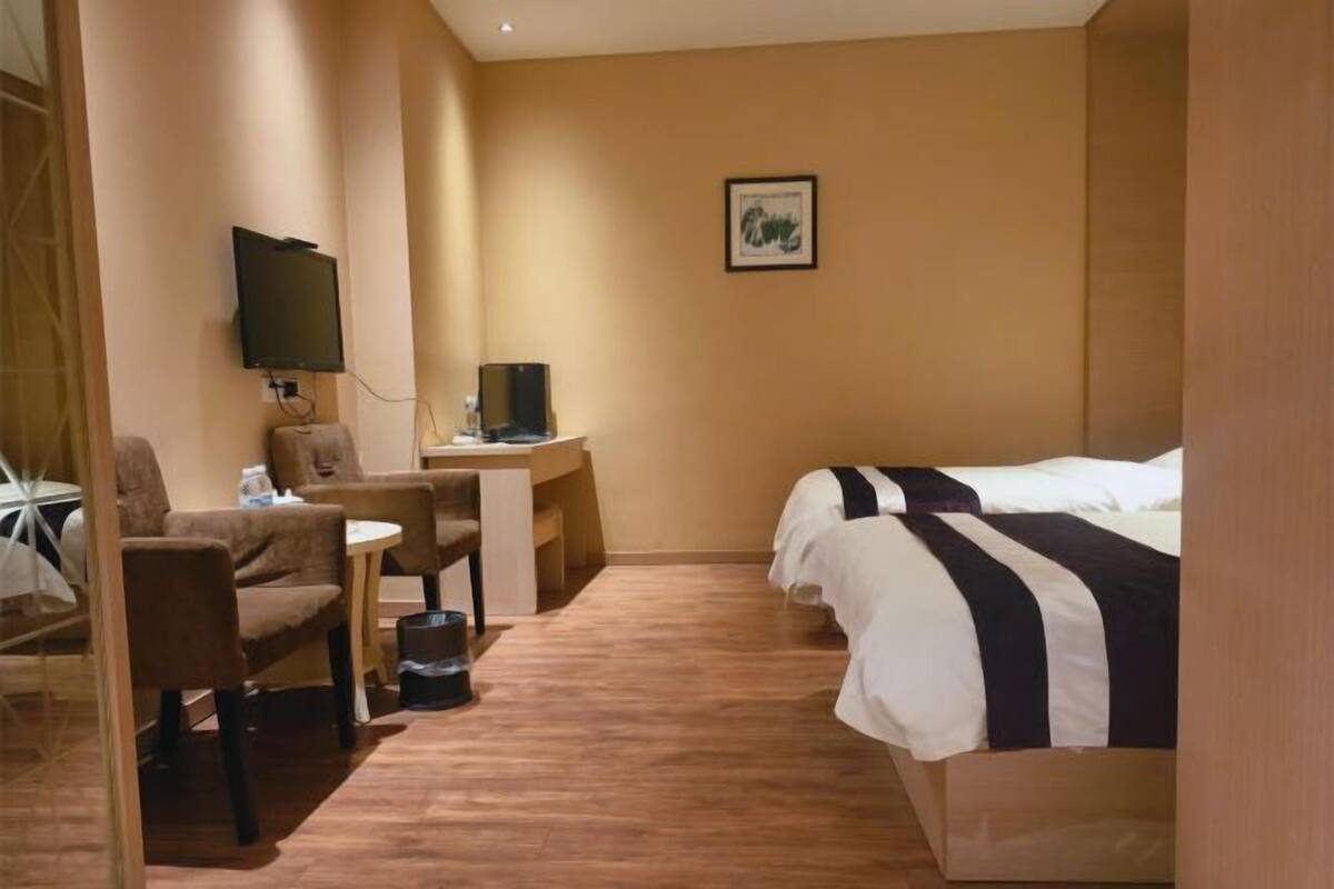 Une chambre d’hôtel avec un lit, un bureau, une chaise, une télévision et un tableau au mur.