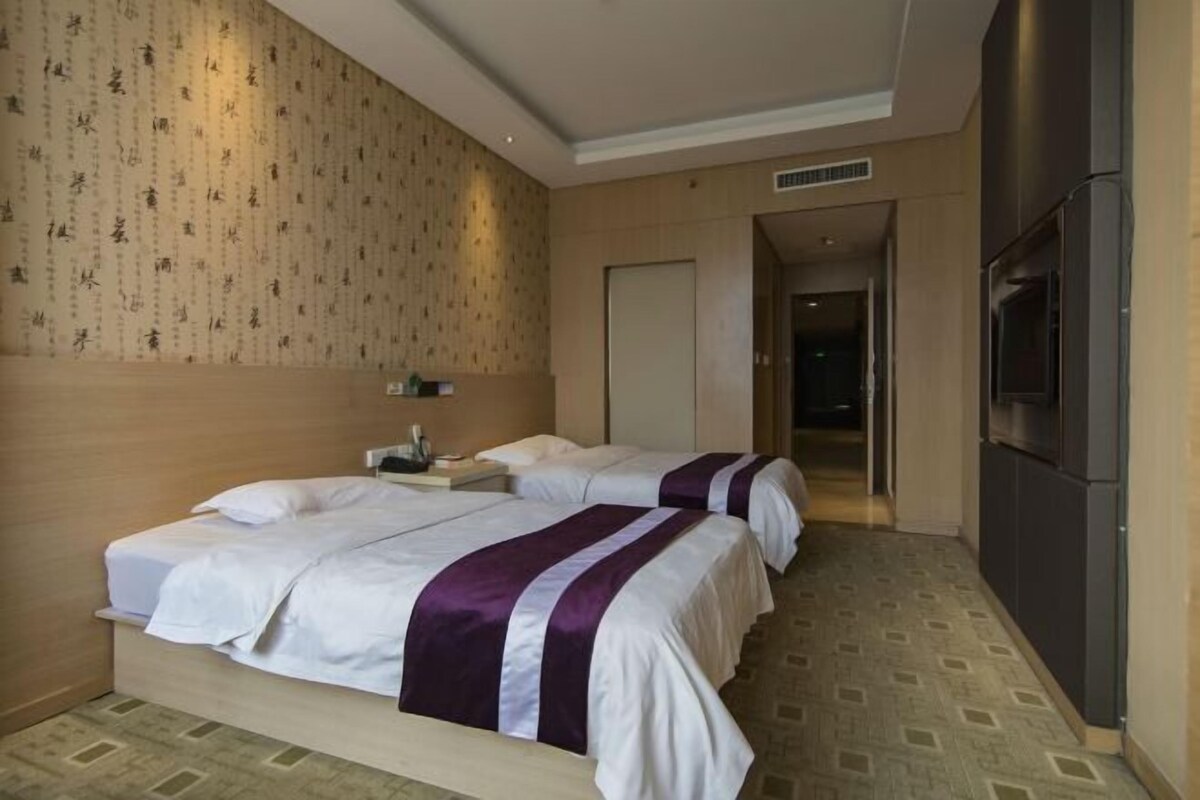 Habitación de hotel con dos camas, un televisor y una pared de madera con diseños.