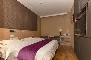 Una habitación de hotel con una cama grande, un escritorio, un televisor y un minibar.