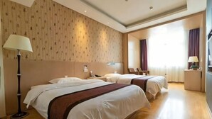 Habitación de hotel con dos camas, una mesita de noche con lámpara, y un ventanal grande con cortinas.