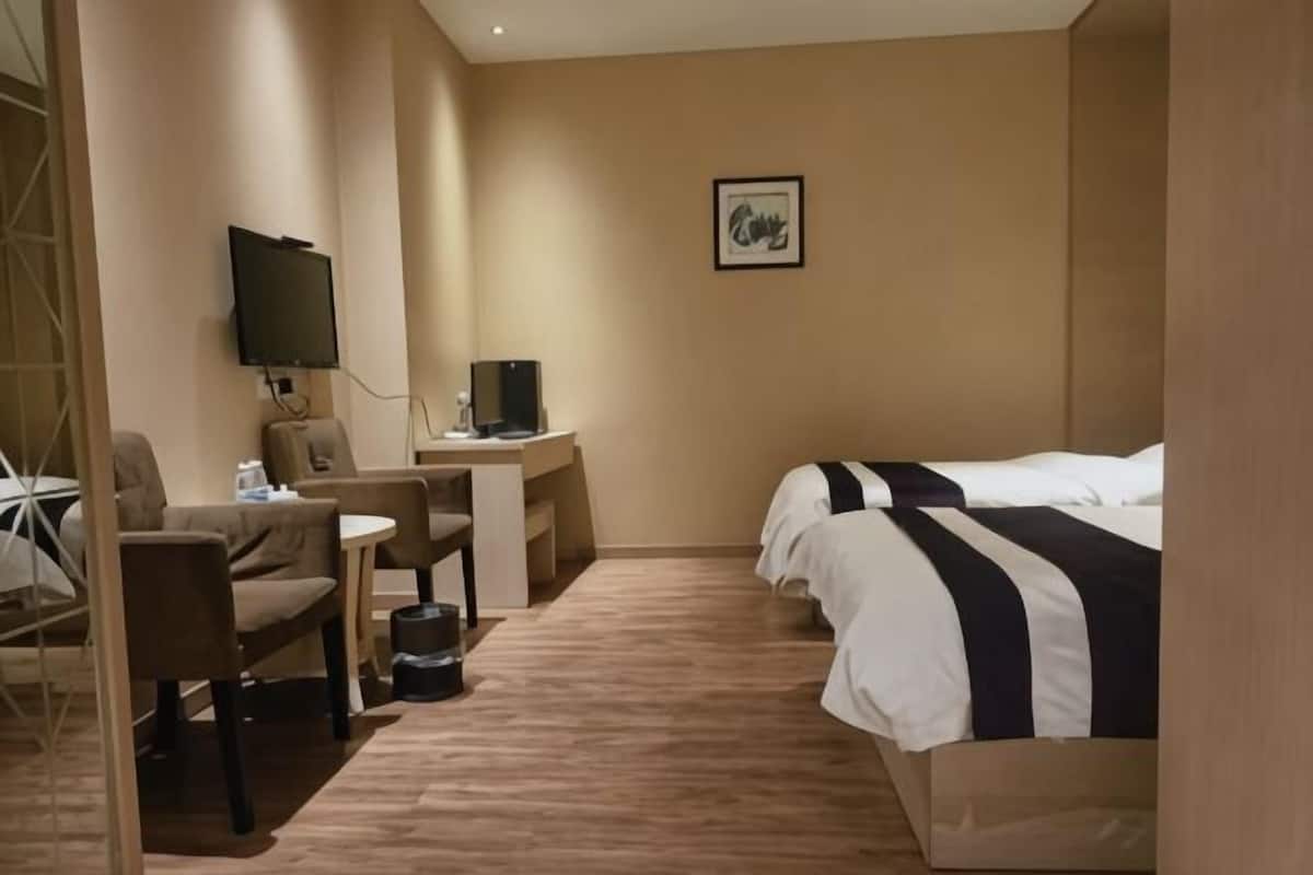 Une chambre d’hôtel équipée d’un lit, d’un bureau avec un ordinateur, d’une chaise et d’un téléviseur.