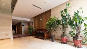 Un vestíbulo con mostrador de recepción, plantas en macetas y un banco de madera.
