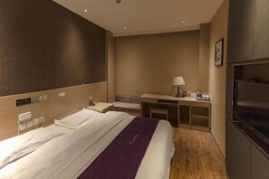Una habitación de hotel con una cama grande, un escritorio con lámpara y un televisor.