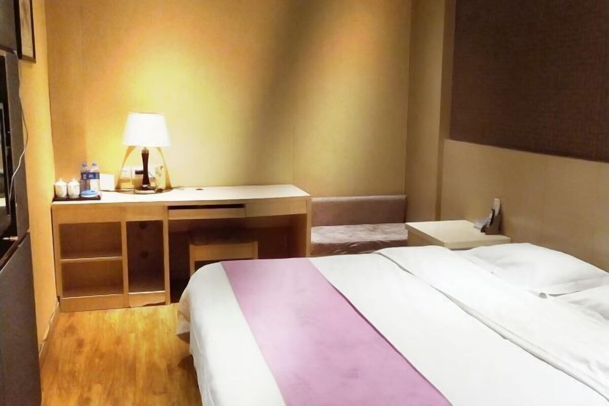 Una habitación de hotel con cama, escritorio, lámpara y mesita de noche.