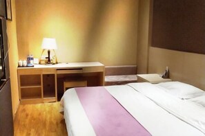 Una habitación de hotel con cama, escritorio, lámpara y mesita de noche.