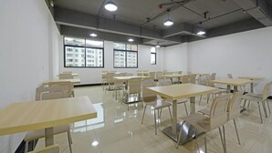 A spacious room with multiple tables and chairs, large windows, and a high ceiling with exposed pipes. - Longting Holiday Hostel (Fengkai)