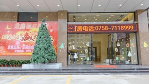 A hotel entrance with a Christmas tree decoration, a large promotional sign, and a contact phone number displayed above the entrance. - Longting Holiday Hostel (Fengkai)