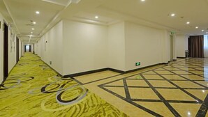 A hotel corridor with a patterned carpet, a tiled floor, and a series of doors along the walls. - Longting Holiday Hostel (Fengkai)