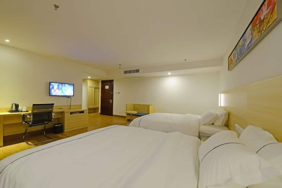 A hotel room with two beds, a desk with a chair, a television, and a painting on the wall.