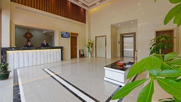 A hotel lobby with a reception desk, a television, and a seating area with a coffee table. - Longting Holiday Hostel (Fengkai)
