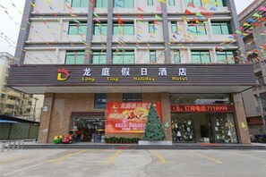 A hotel entrance with a signboard, a large advertisement, and a parking lot. - Longting Holiday Hostel (Fengkai)