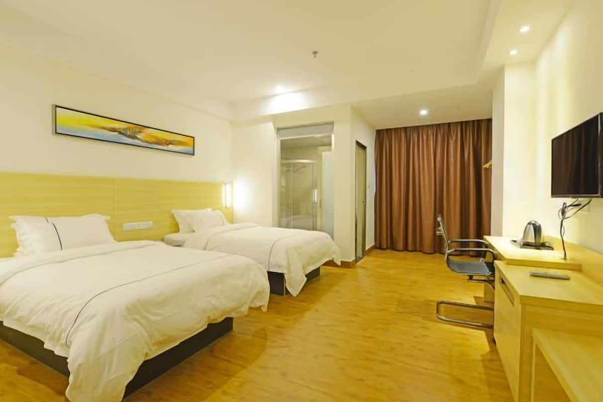 A hotel room with two beds, a desk with a chair, a television, and a painting on the wall.