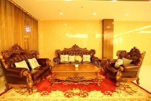 A room with two ornate leather sofas, a wooden coffee table, and a red patterned rug. - Silvery Waterfall Hotel (Daguan)