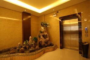 An elevator with a marble wall and a small indoor garden. - Silvery Waterfall Hotel (Daguan)