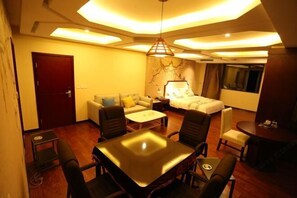 Quarto de hotel com sofá, cama, mesa de jantar e uma pequena televisão.
