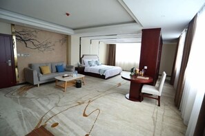A hotel room with a bed, a sofa, a dining table, and a chair. - Silvery Waterfall Hotel (Daguan)