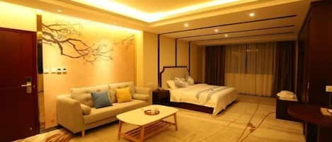 A hotel room with a bed, a sofa, a coffee table, and a desk.