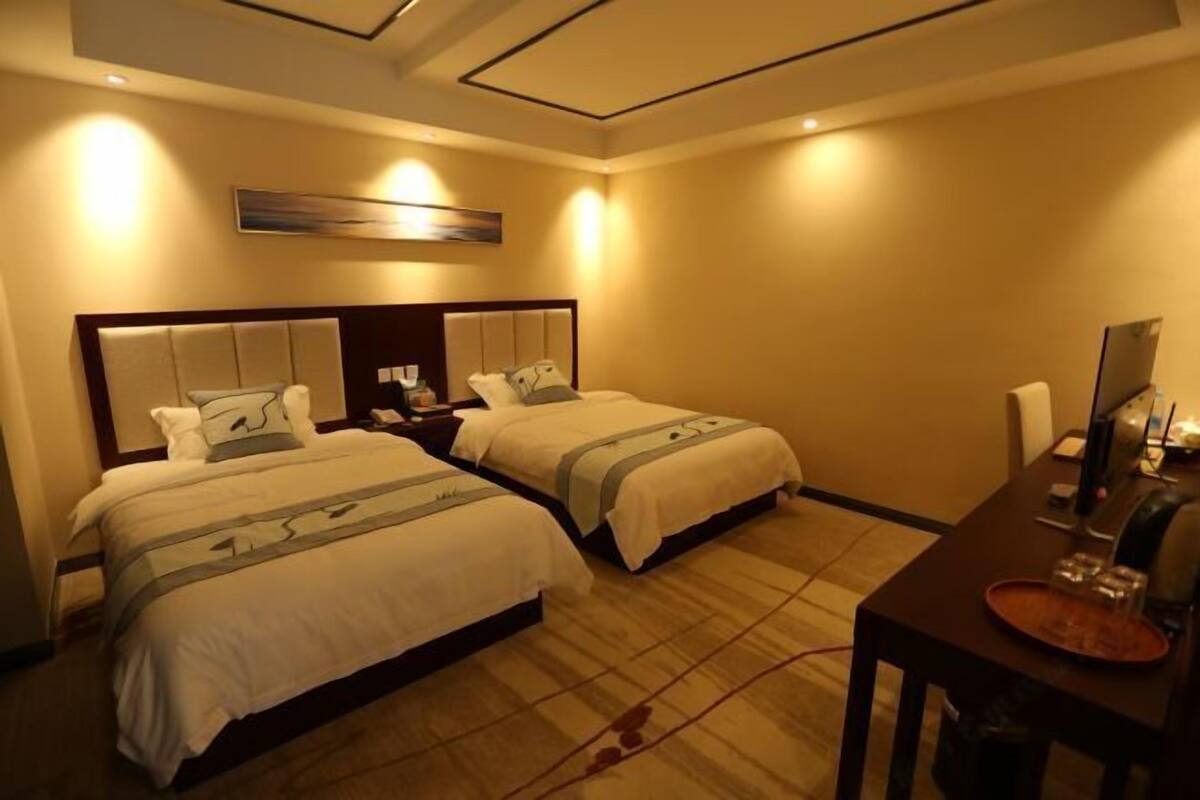 A hotel room with two beds, a desk, and a chair.