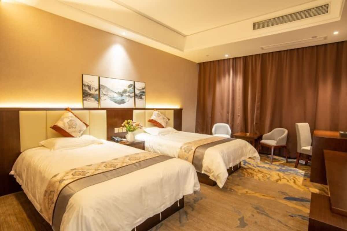A hotel room with two beds, a desk, and a chair.