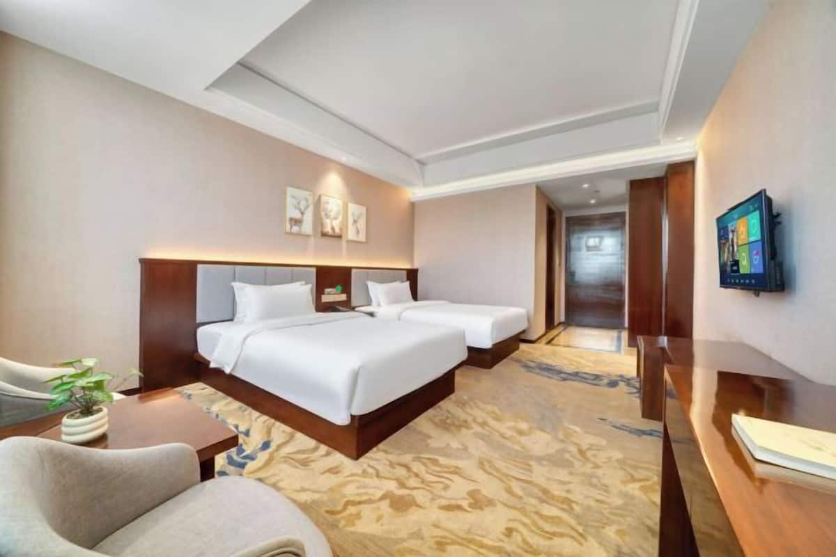 A hotel room with a large bed, two bedside tables, a desk, and a chair.