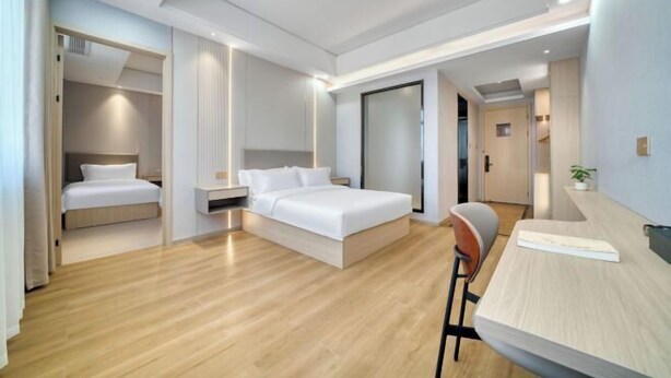 A modern hotel room with a bed, a desk, and a chair. - Waterfront Garden Hotel (Huzhou)