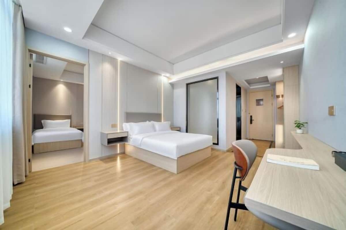 A modern hotel room with a bed, a desk, and a chair.