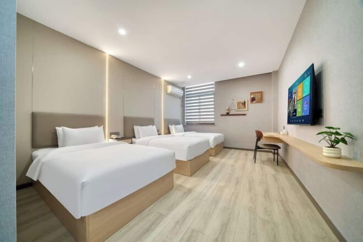 A modern hotel room with two beds, a desk, and a TV.