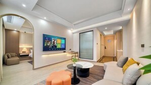 A modern living room with a flat-screen TV, a round coffee table, and a sofa with cushions. - Waterfront Garden Hotel (Huzhou)