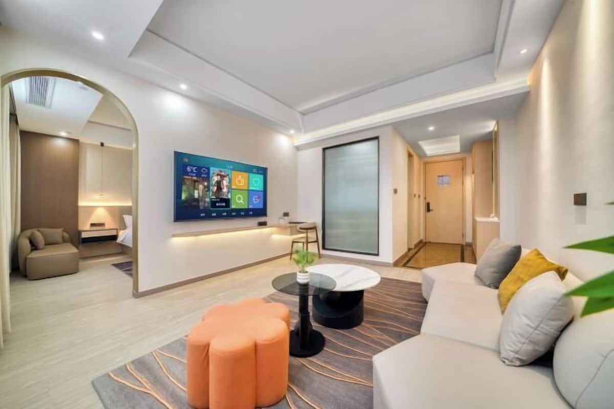 A modern living room with a flat-screen TV, a round coffee table, and a sofa with cushions.