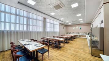 A conference room with multiple tables and chairs, large windows, and a ceiling with recessed lighting.