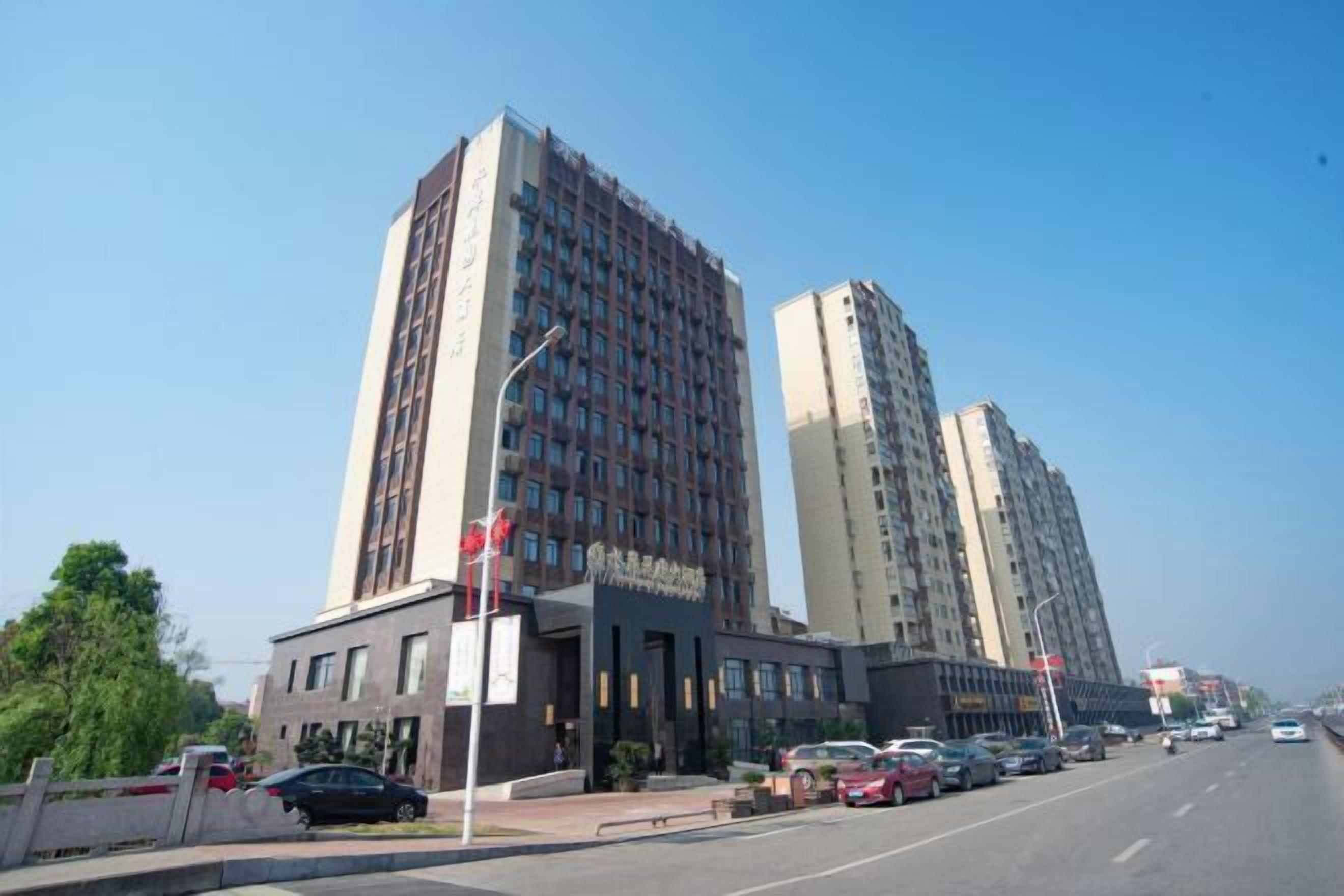 A modern building with multiple floors, a parking lot, and a clear sky.