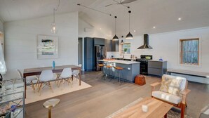 Een ruime woonkamer met een eettafel, barstoelen en een keukenbar.