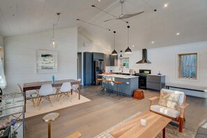 Uma sala de estar ampla com uma mesa de jantar, banquetas de bar e uma cozinha com balcão.