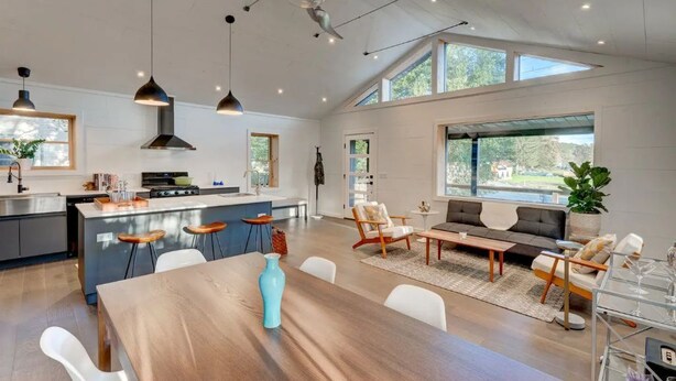 Een ruime woonkamer met een eettafel, een bank en een keuken op de achtergrond.