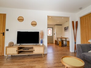A living room with a television, wooden furniture, and a wicker chair. - Rollin' Dunes (Grimsby)