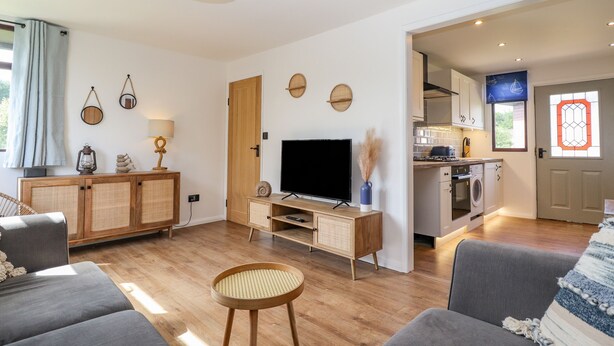 Una sala de estar moderna con un televisor de pantalla plana, un mueble de madera y un taburete de ratán.