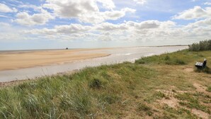 Una playa extensa y abierta con cielo despejado y horizonte lejano.