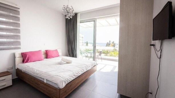 Ein modernes Schlafzimmer mit einem großen Bett, einem Flachbildfernseher und einem Balkon mit Blick.