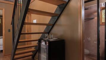 A modern staircase with wooden steps and metal railings, leading to an upper floor. A small table with a television is placed on the lower landing.