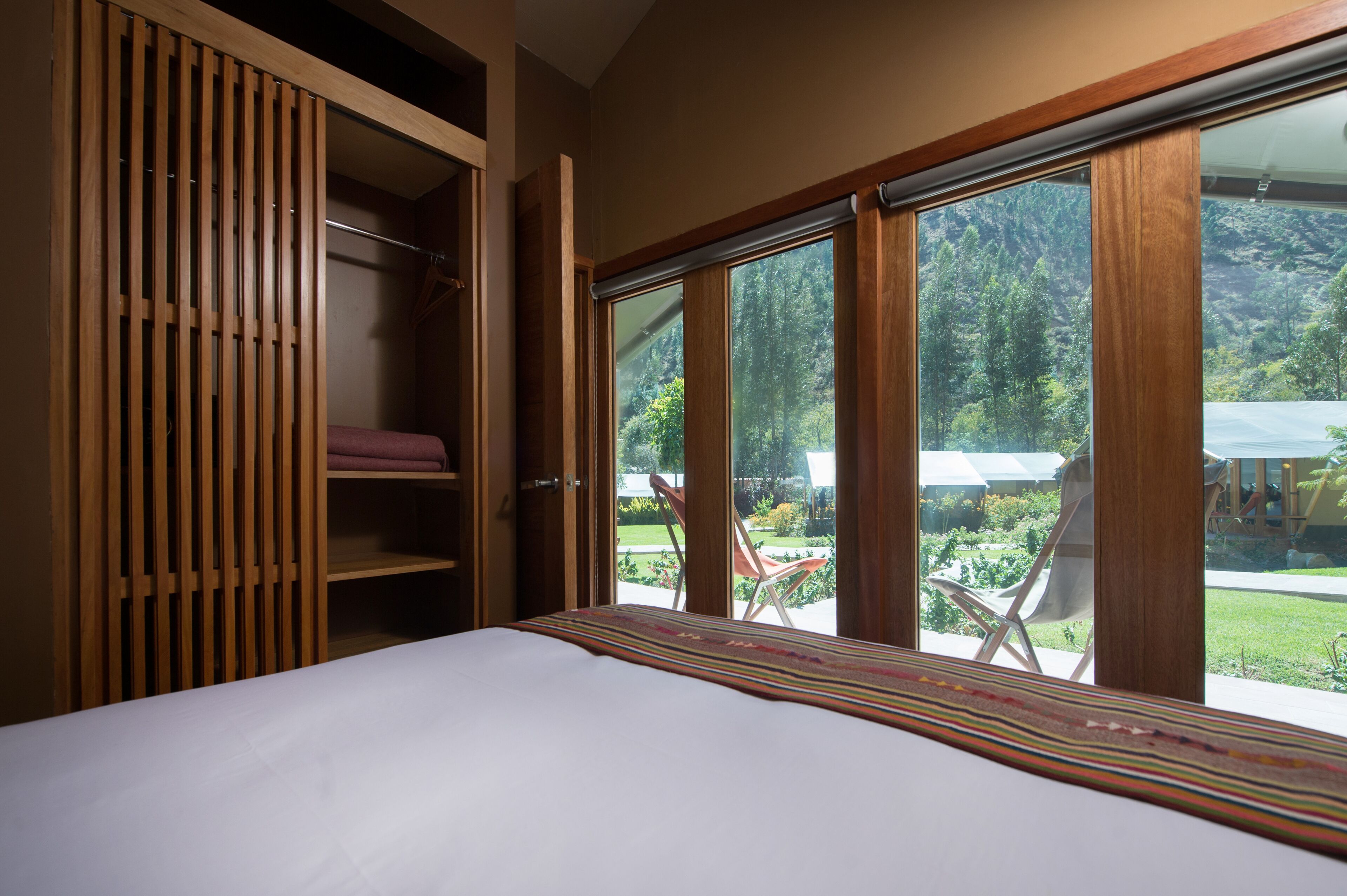 Une chambre avec une grande fenêtre, un lit et une armoire en bois.