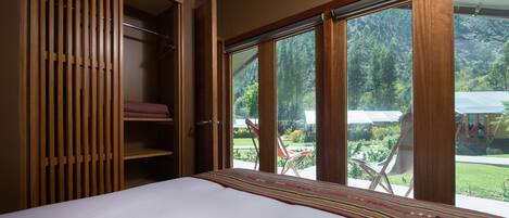 Une chambre avec une grande fenêtre, un lit et une armoire en bois.