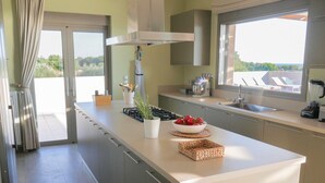 A modern kitchen with a central island, a stove, and a large window providing a view of the outdoors.