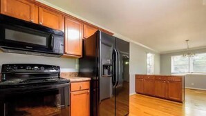 Una cocina con armarios de madera, un refrigerador negro y una estufa.