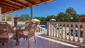 An outdoor patio with wicker furniture, a pool, and a white balustrade.