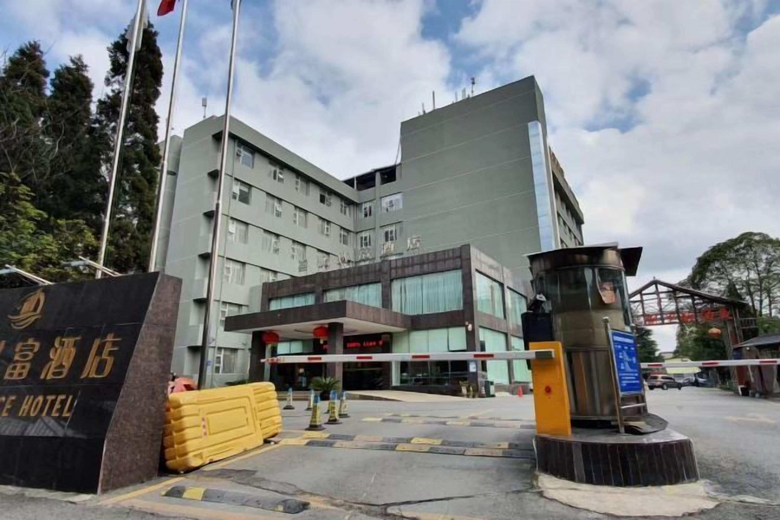 A hotel entrance with a modern building, a signboard, and a security booth.