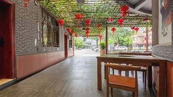 A corridor with a brick wall, a wooden table, and red lanterns.